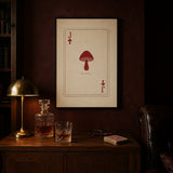 Jack of Spores print framed in black above a walnut cabinet with a decanter and a deck of cards, shown in 50x70cm